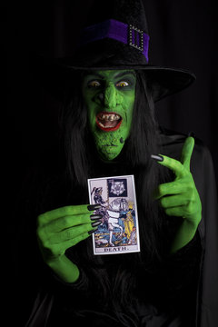 Wicked witch and tarot card, black background.