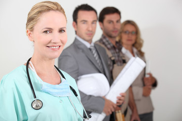 Female nurse stood next to four professionals from different - obrazy, fototapety, plakaty