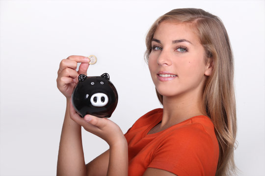 Teenager placing money in piggy bank