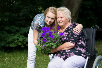 Seniorin im Rollstuhl mit ihrer Großtochter