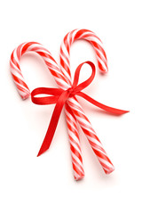 Closeup of candy canes tied with ribbon bow on white