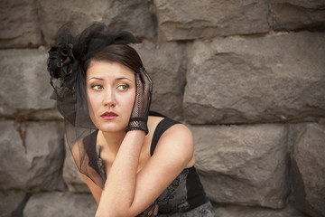 girl in a black hat against the stone wall