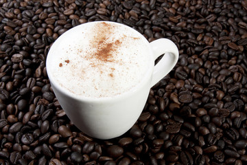 a glass of hot cappucino on coffee bean background.