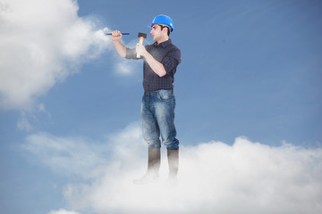Photomontage of a workman driving a nail in the clouds