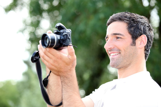 Happy relaxed man looking at the screen of his DSLR camera