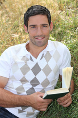 Man laid in field with book in hand