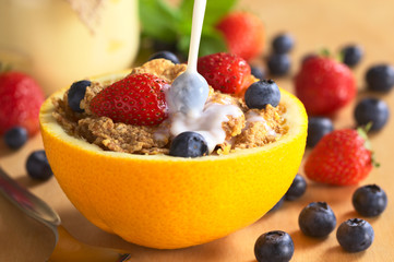 Pouring milk over wholewheat cereal with fresh fruits