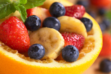 Fruit salad in half orange with banana slices and berries