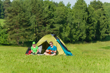 Young camping couple cooking meal play guitar