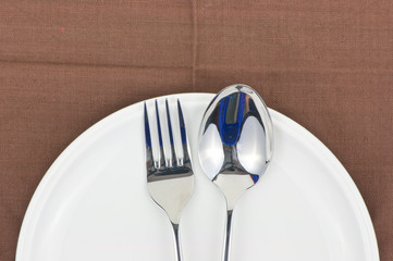 Spoon and fork on a dish as a dining room serving.