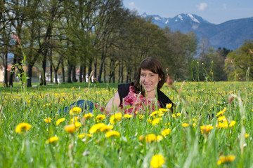 Junge Frau liegt im Gras und L&ouml;wenzahn
