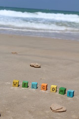 The word WELCOME written on colorful wood cubes, at the beach