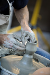 the hands of a potter shaping a vase on the lathe..