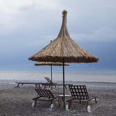 Straw Umbrellas with Sun Loungers on Beach