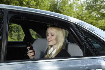 Naklejka premium Woman sits in a car and holds her mobile phone in her hand