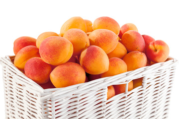 White wicker basket full of fresh apricots