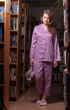 Girl in pajamas and slippers at night in the library