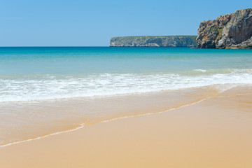 Fototapeta na wymiar Sunny sandy beach with slightly waves