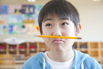 口と鼻の間に鉛筆を挟む小学生男子