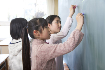 黒板に絵を描く小学生女子