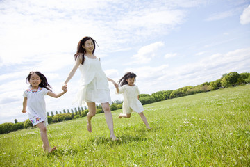 草原を走る女の子2人と若い女性
