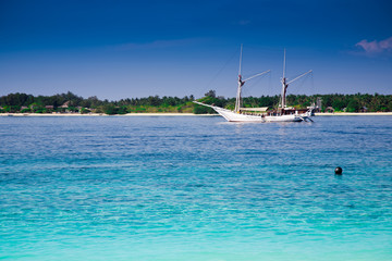 Obraz premium Sailboat at a turquoise tropic island