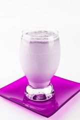 Blueberry milkshake or smoothie in glass on pink saucer