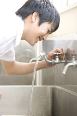 Obraz na płótnie Canvas 水道水を飲む男子中学生