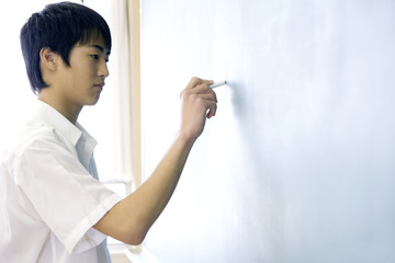 黒板に解答を書く男子中学生