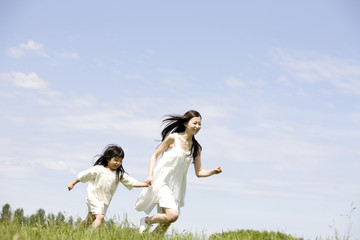 草原を走る女性と女の子