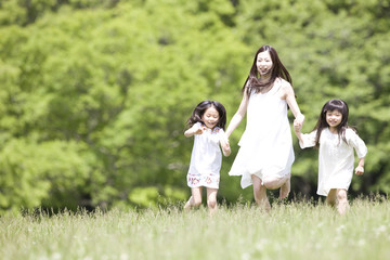 手を繋いで走る大人の女性と2人の子供