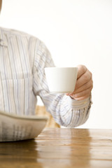 コーヒーカップを持つシニア男性の手元