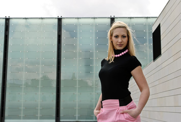 blonde girl posing in front of glass building