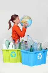 Young girl kissing the planet next to her recycling