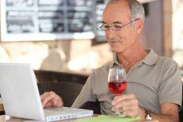 Senior man using his laptop in a cafe