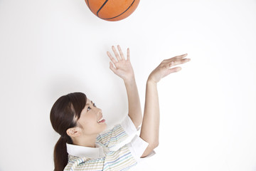 バスケットボールを両手で放り上げる女性