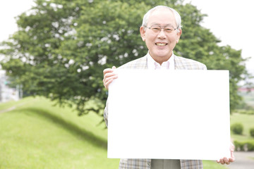 公園でメッセージボードを持つ老人