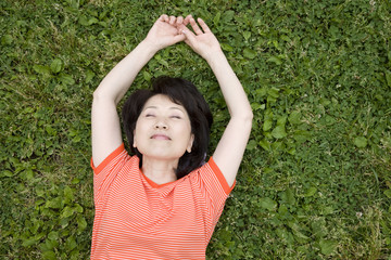 公園の芝生に仰向けに寝転がる女性