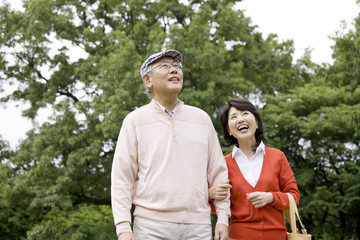 腕を組みながら公園を散歩する老夫婦