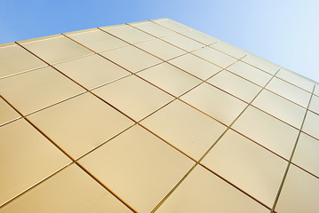 Facade wall of golden squares against the sky.