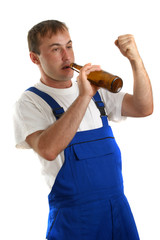 Handwerker mit blauer Latzhose trinkt eine Flasche Bier