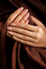 Human hands with classic french-style manicure wrapped with silk
