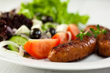 Grilled sausage with greek salad and herbs