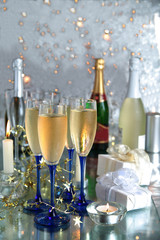 Champagne in glasses,gifts and lights on silver background.