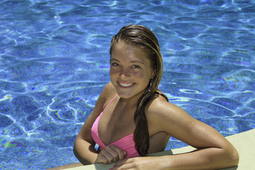 portrait of a teenage girl in pink bikini in a swimming pool