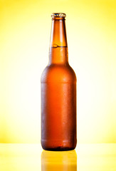 Brown full bottle fresh cold beer covered with condensate on yel