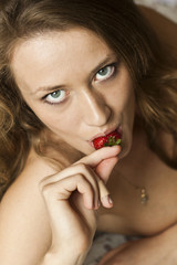 Beautiful curly brunette attractive eating strawberries