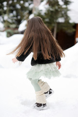 Fototapeta na wymiar Brunette girl in tutu skirt and fur jacket dances in the snow