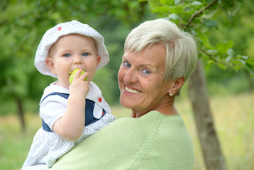 Child on grandmothers arm eating an apple