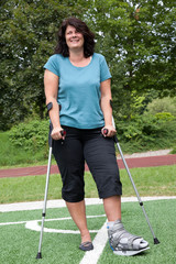 Frau mit Gipsbeim am Fußballplatz